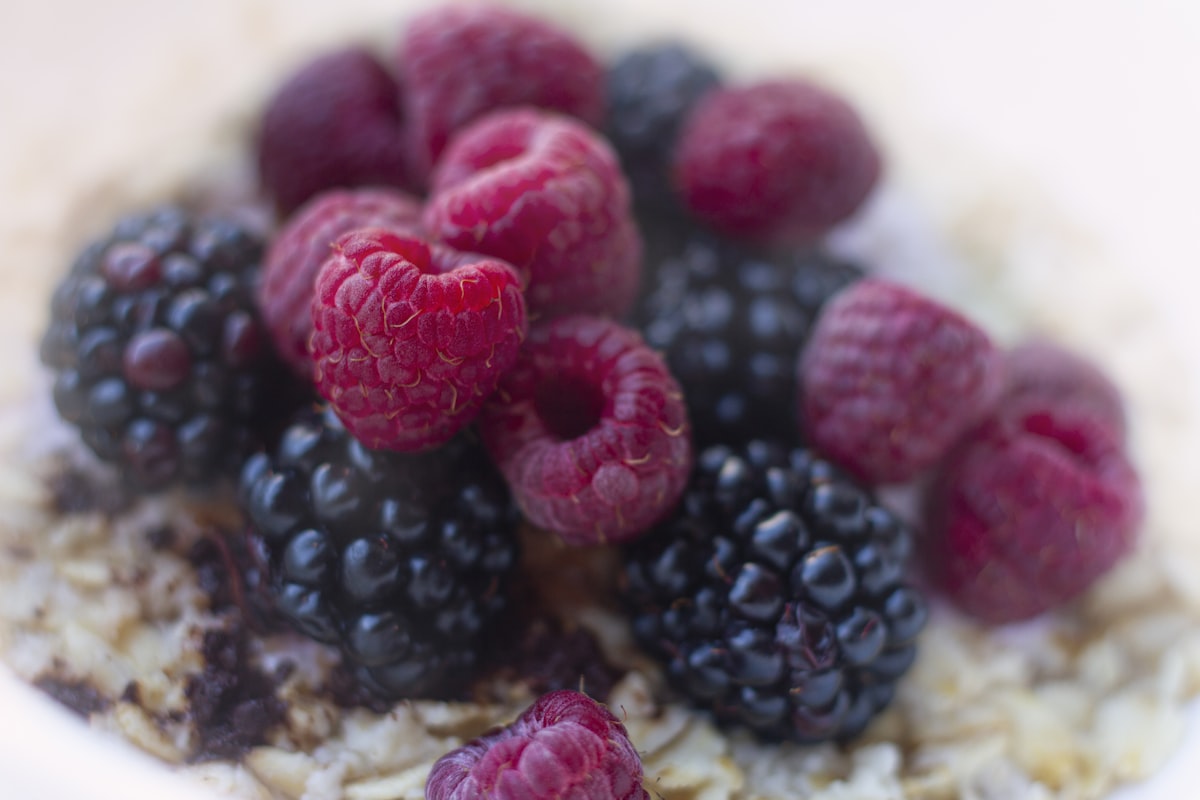 A bowl of oatmeal topped with raspberries and blueberries
